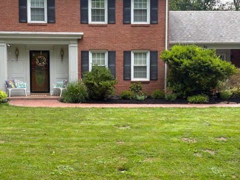 Front yard landscape beds and shrubs at a brick colonial home