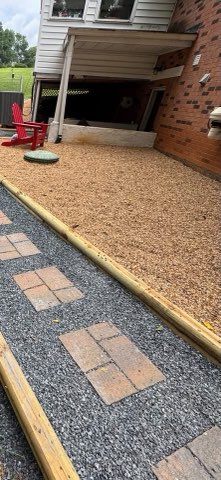 Paver stepping stone path set in gravel with timber borders beside a home