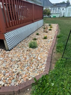 River rock bed with paver edging and plantings along a deck
